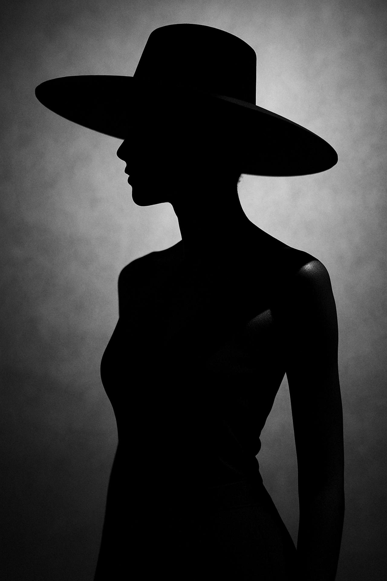 Fashion model in black fedora hat, monochrome silhouette, vintage clothing