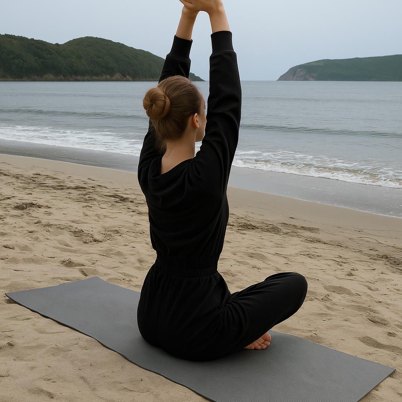 Person in yoga pose on beach mat by the sea