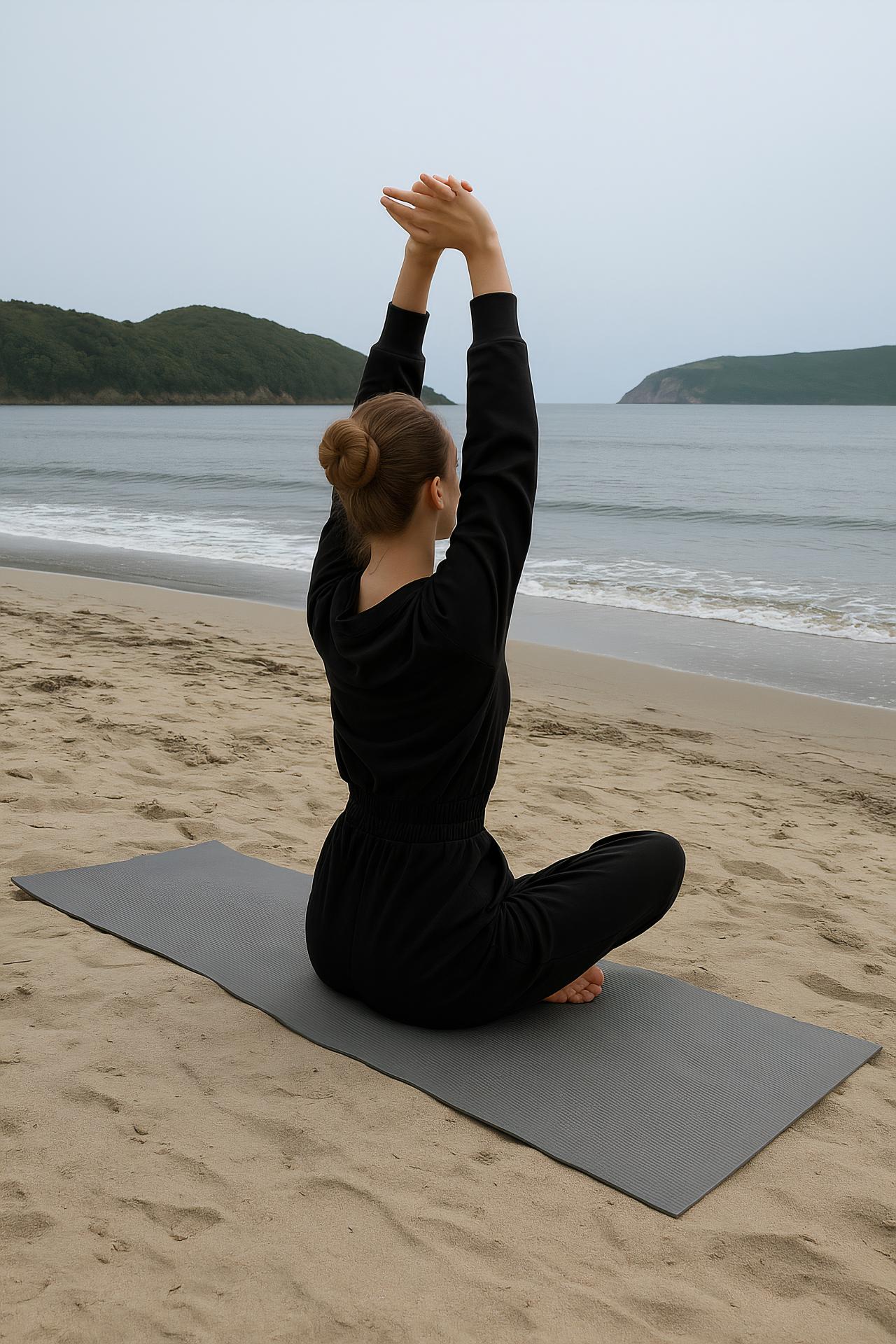 Person in yoga pose on beach mat by the sea