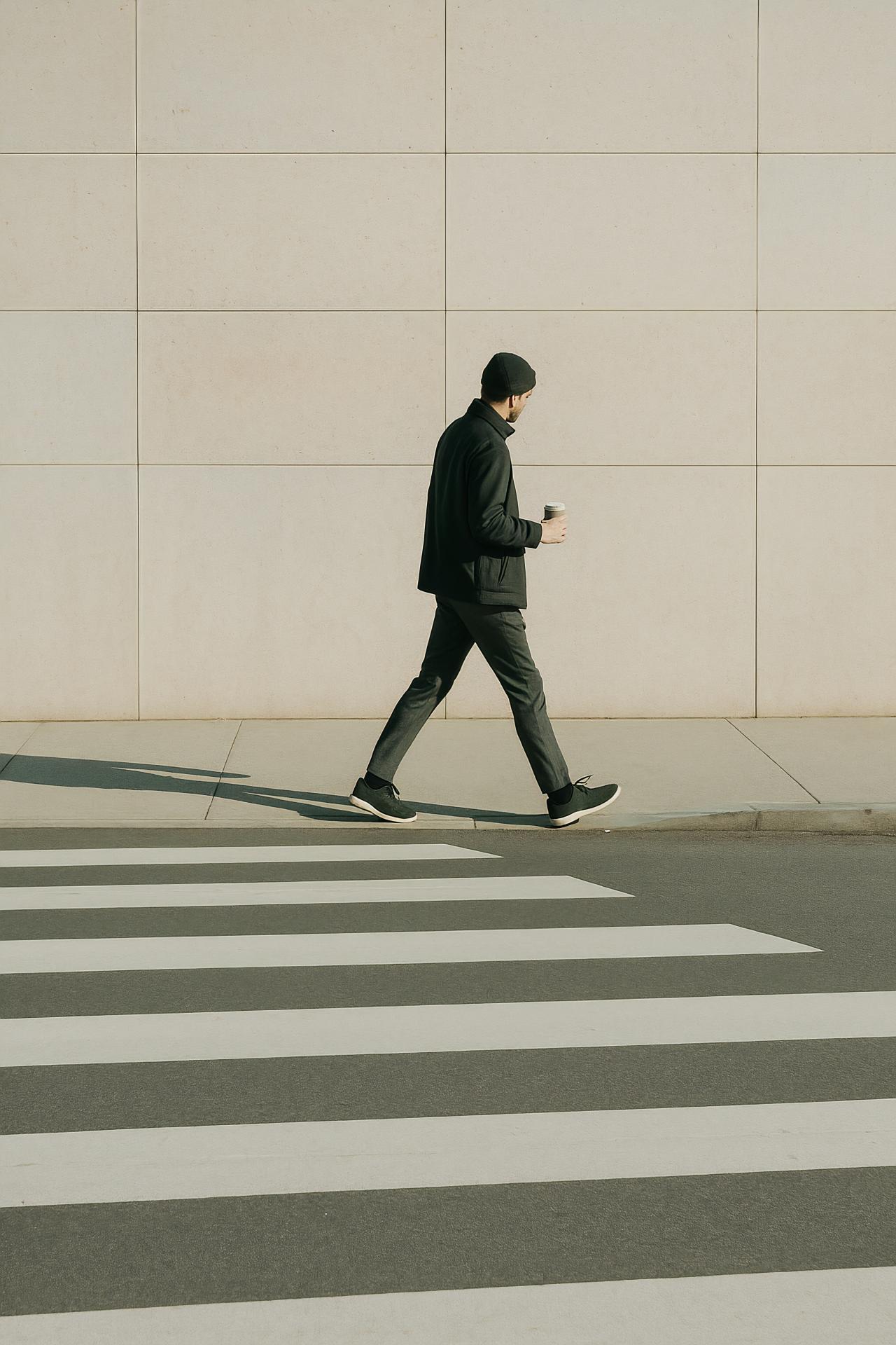 Person standing near pedestrian crossing with black shoe on asphalt road