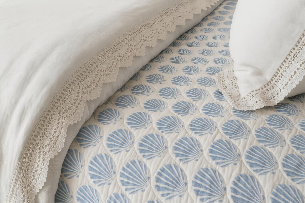 Bed with stylish linens, pillows, and throw pillows in a cozy bedroom