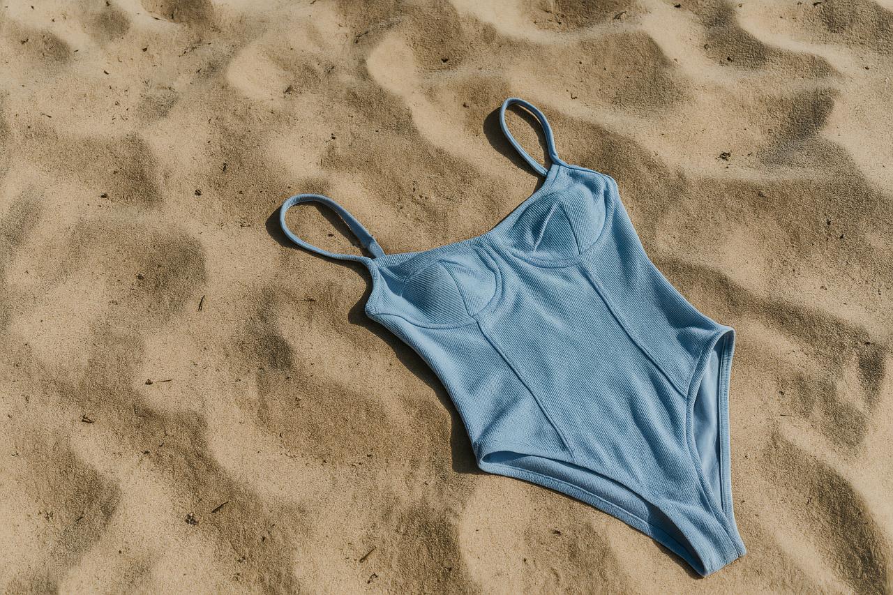 Fashionable one-piece swimsuit model on sandy beach