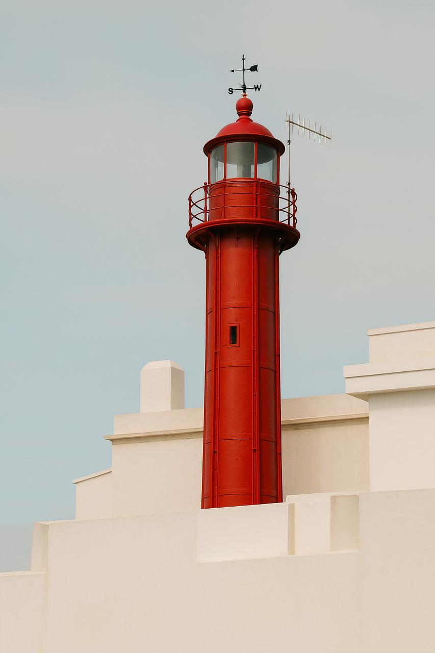 Red cylindrical lighthouse tower beacon in daylighting