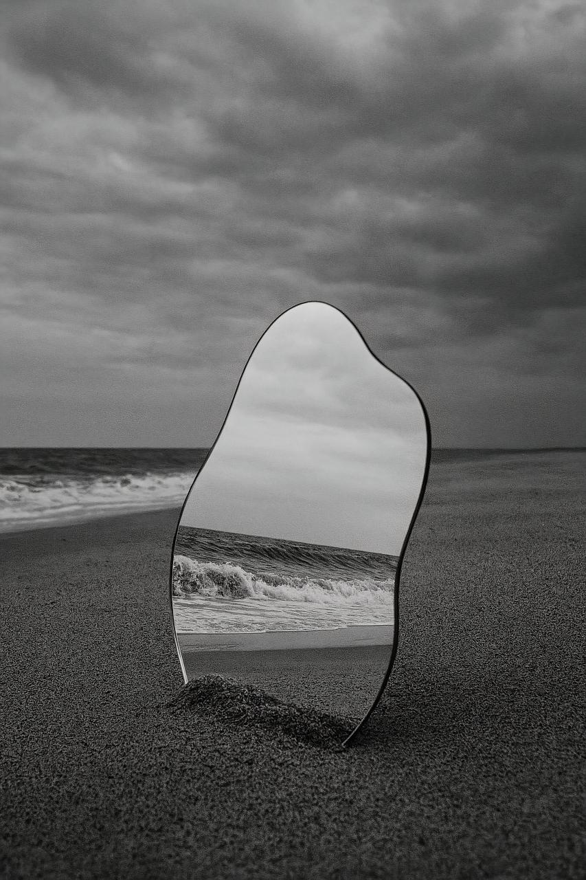 Silver sea meeting beach with chair, monochrome ocean reflections