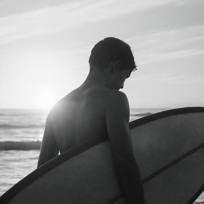 Surfer riding black surfboard on ocean wave