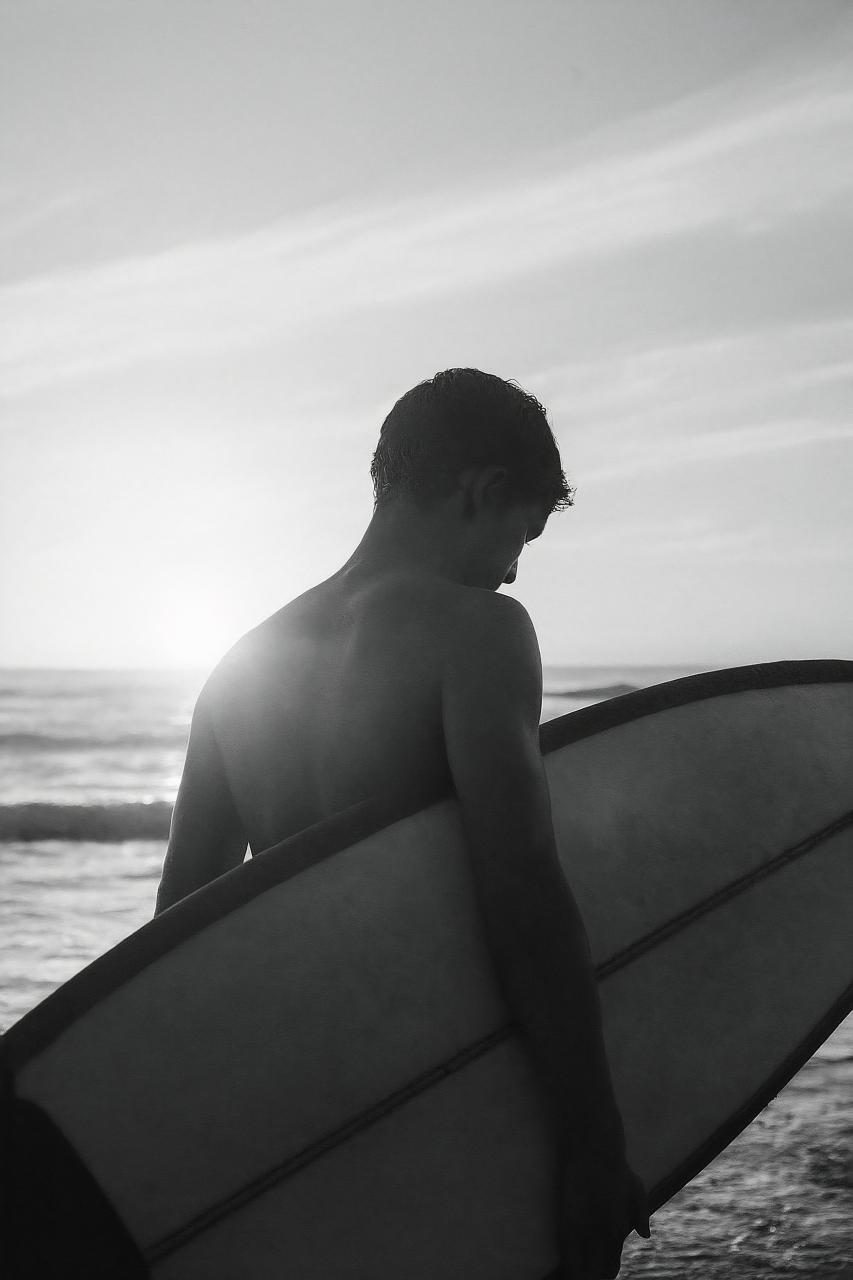Surfer riding black surfboard on ocean wave