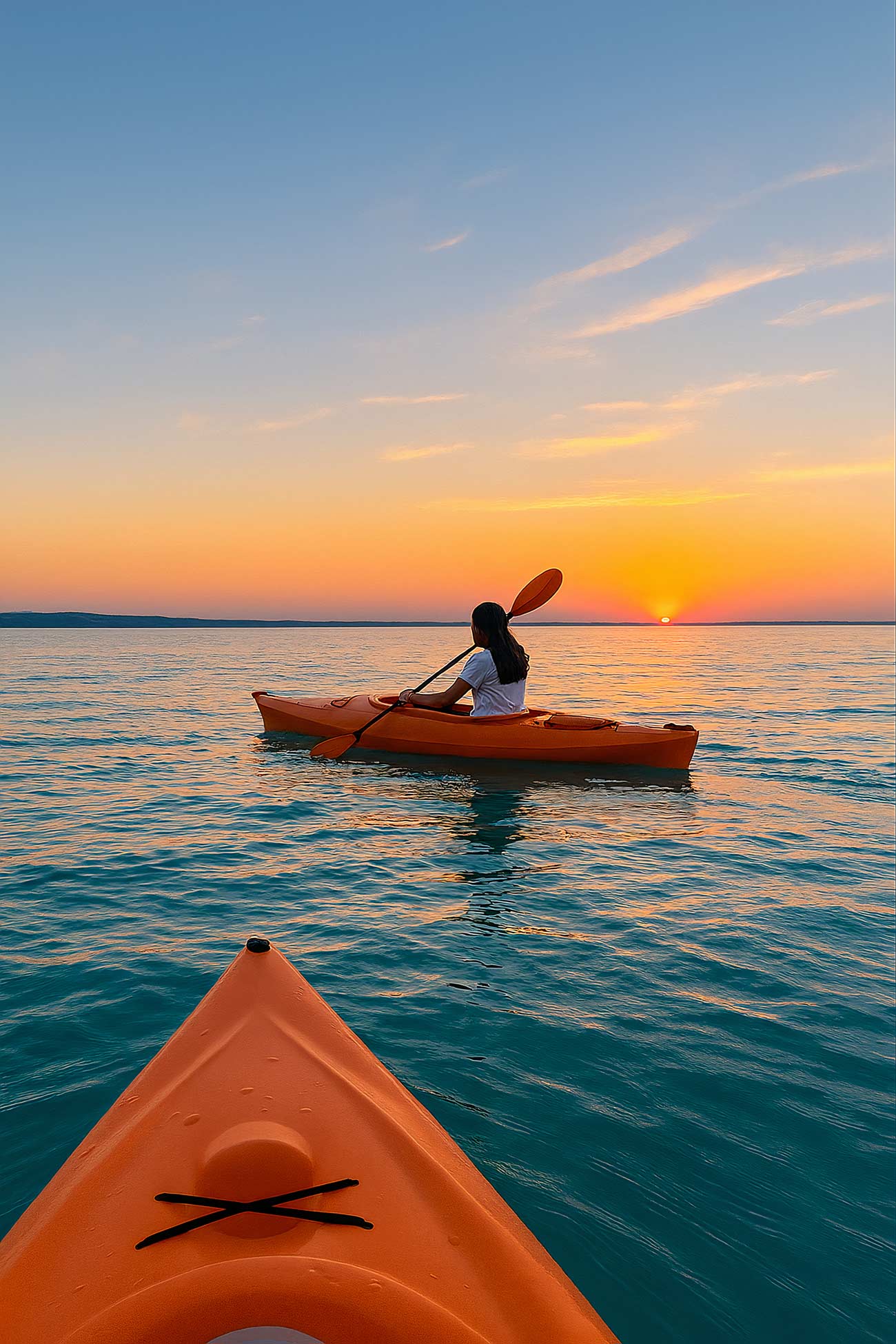 Orange sea kayak on tranquil ocean at sunset