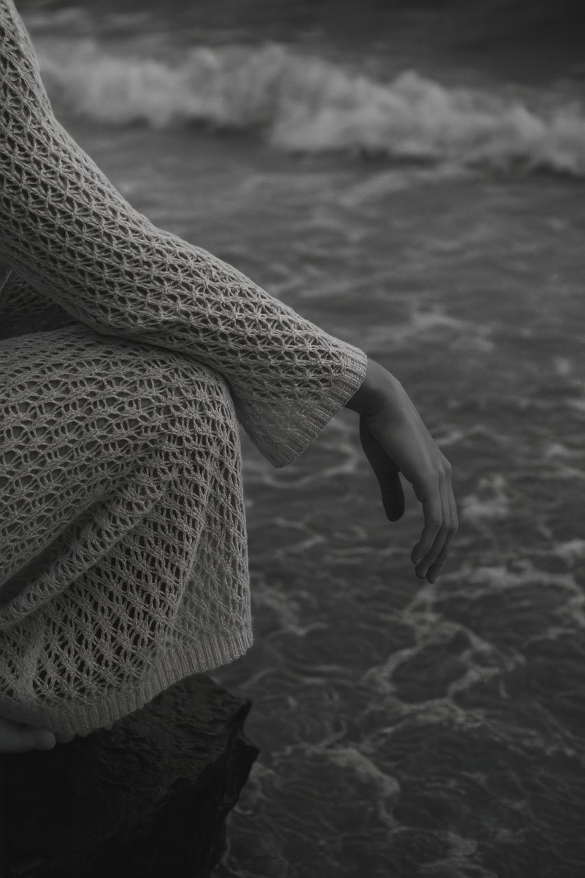 Monochrome beach scene with waves, footprints, and woolen texture