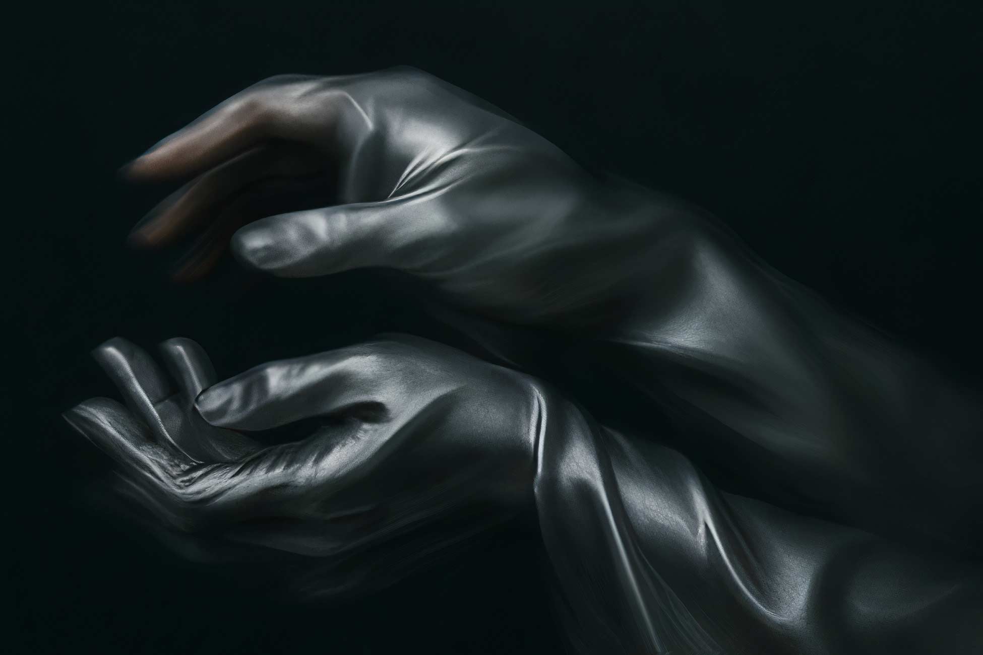 Hand with black nails and silver ring emerging from leather jacket
