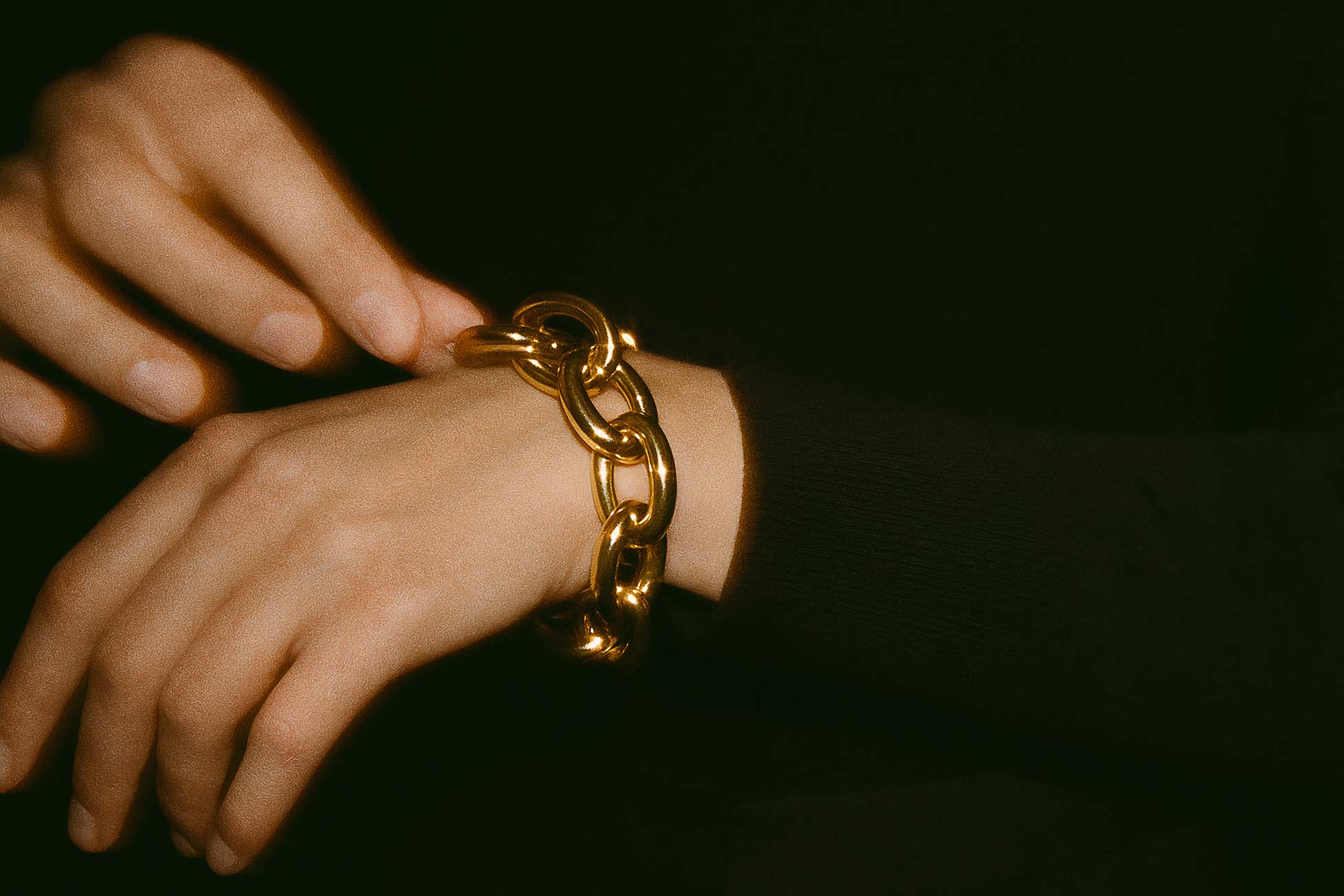 Hand with jewellery including bracelet, chain, rings, and engagement ring