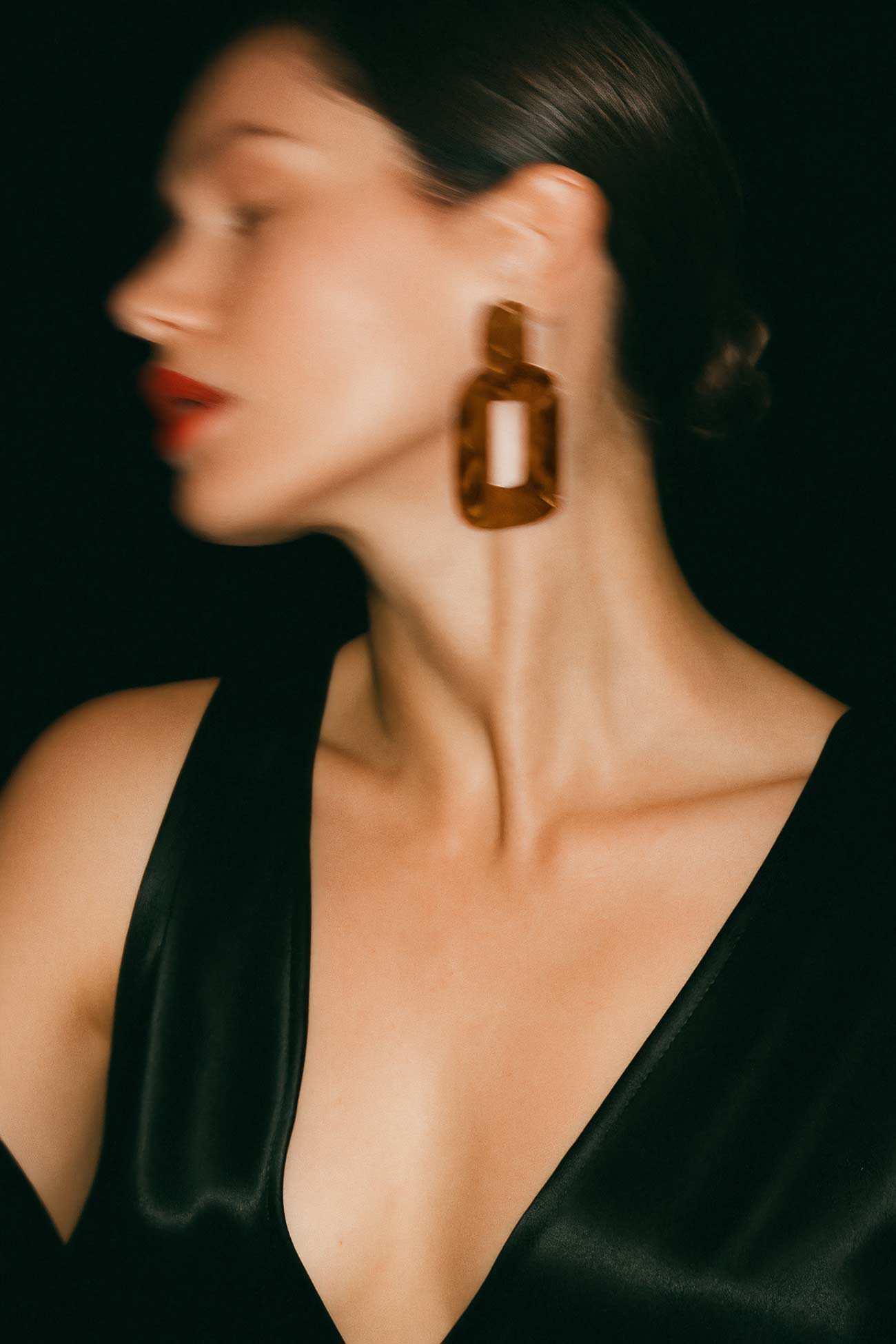 Fashion model with jewelry showcasing elegant black hair and stylish makeup.