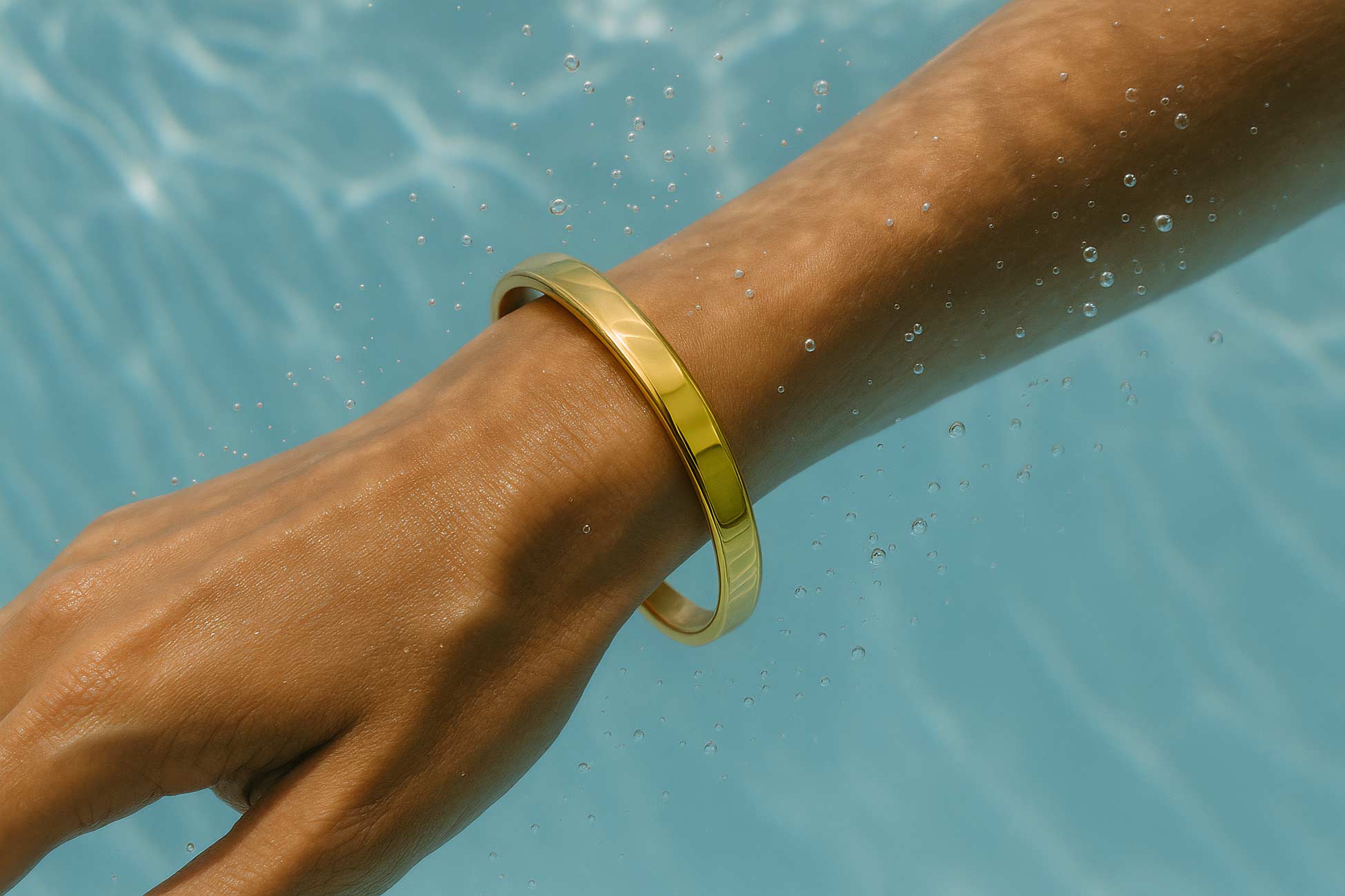 Person\'s hand with bracelet, bangle, ring by swimming pool
