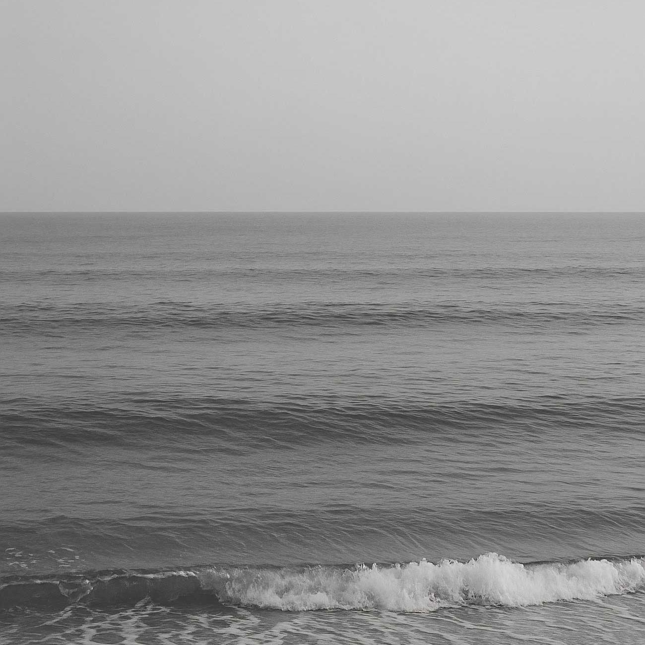 Monochrome white ocean wave crashing on beach