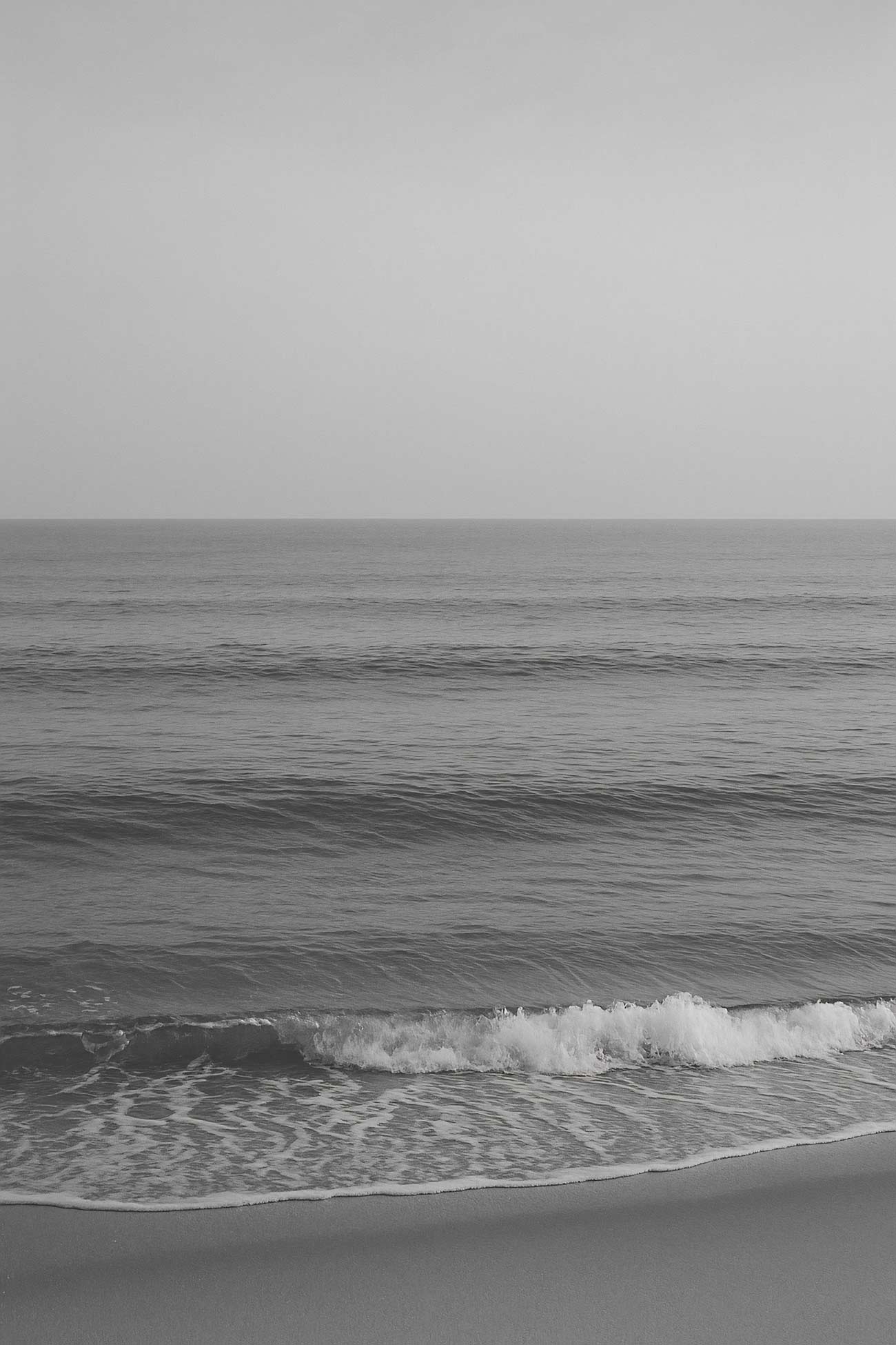 Monochrome white ocean wave crashing on beach